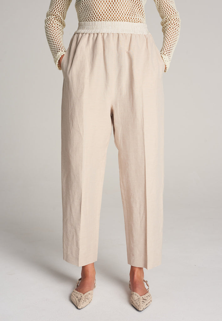 FRENKEN Cave beige trouser with a white elastic waistband and side pockets. Accented with softly pressed creases for the perfect fitting. Also available in black.