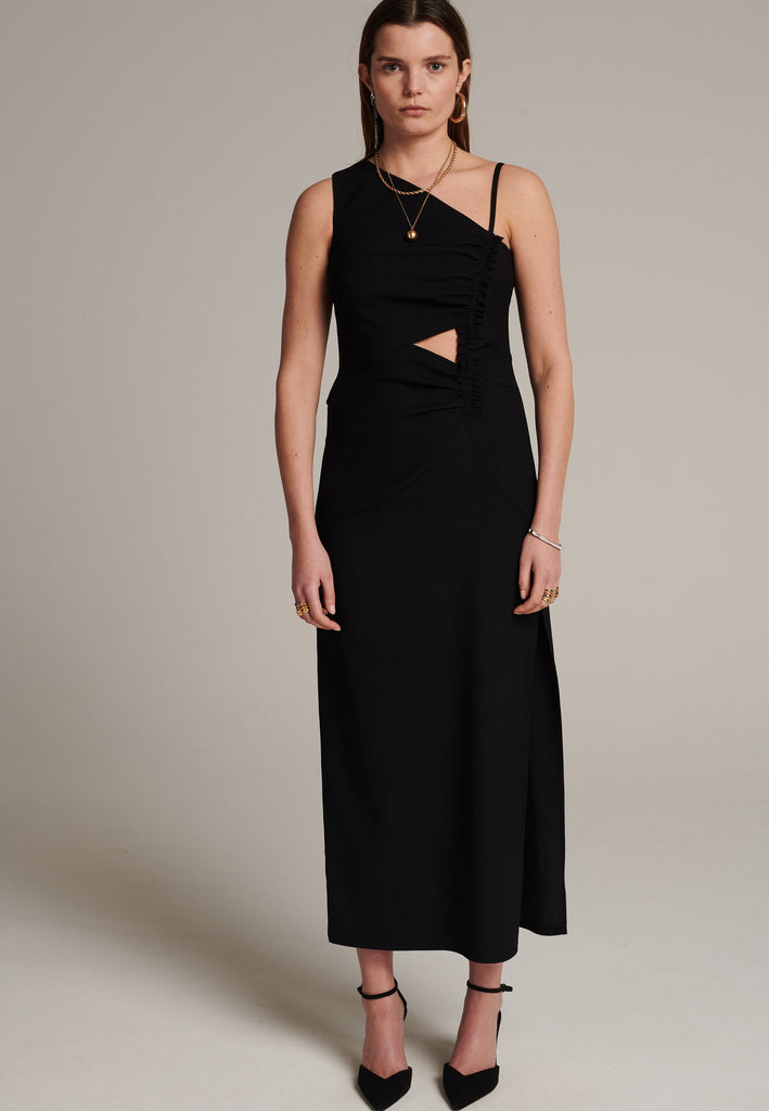 Long evening dress with an asymmetric design made of stretch black wool blend with a subtle gathering at the front to emphasize the silhouette. It has a unique upper part, one delicate shoulder strap and another wider shoulder strap. It has a leg-lengthening side slit for easy movement.