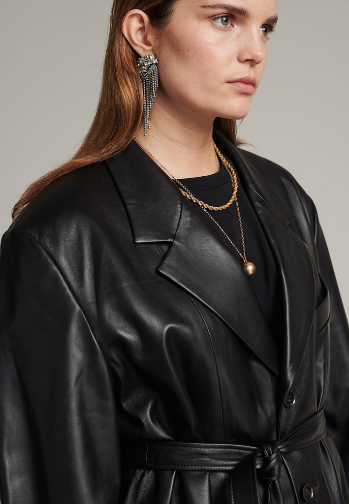Seasonless oversized leather blazer in black with round-shouldered silhouette and coordinating belt that creates some gathering at the back to temper the fitting. Play with it and tie at the smallest part of your waist or tie it at the back for a sense of ease. Pockets, horn buttons and fully lined with. Double fun: wear it as a blazer or as a jacket.