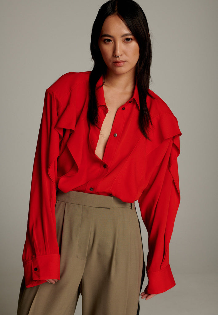 Crepe Georgette shirt with classic red collar. It has black six-hole buttons to adjust the neckline. Special detail with a panel of frills that creates a voluminous look to the garment. This style goes well with jeans and tailoring.