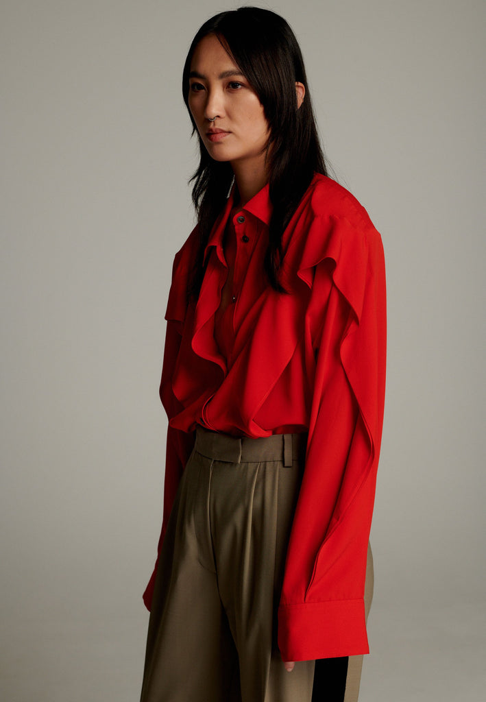 Crepe Georgette shirt with classic red collar. It has black six-hole buttons to adjust the neckline. Special detail with a panel of frills that creates a voluminous look to the garment. This style goes well with jeans and tailoring.