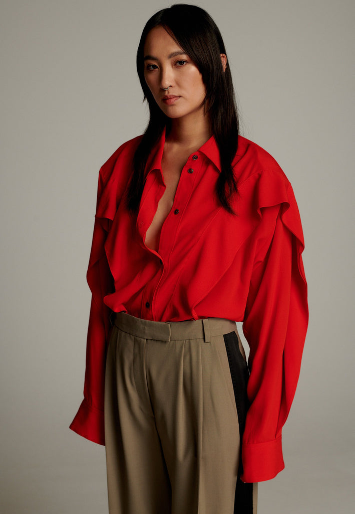 Crepe Georgette shirt with classic red collar. It has black six-hole buttons to adjust the neckline. Special detail with a panel of frills that creates a voluminous look to the garment. This style goes well with jeans and tailoring.
