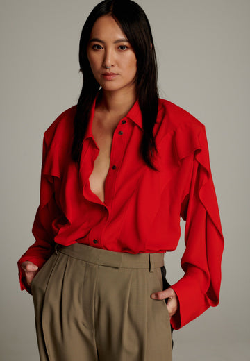 Crepe Georgette shirt with classic red collar. It has black six-hole buttons to adjust the neckline. Special detail with a panel of frills that creates a voluminous look to the garment. This style goes well with jeans and tailoring.
