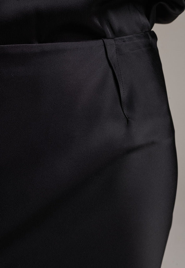 Flowy black skirt with a refined, elongated silhouette. Crafted from lightweight fabric with soft movement and an elegant drape. Front and back darts are intentionally exposed, adding subtle structure and a tailored finish to the fluid shape. A quiet statement piece, effortlessly balancing form and flow.
