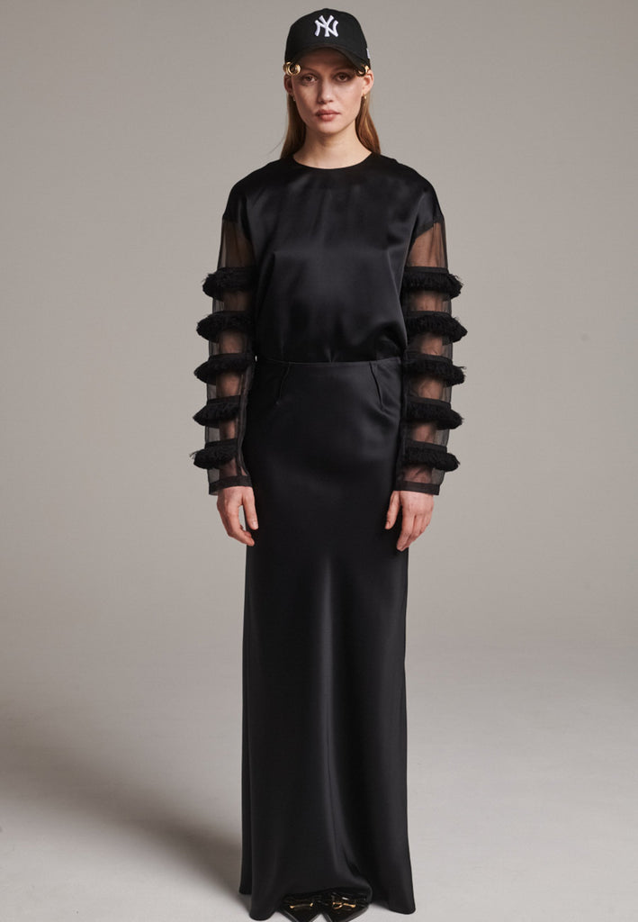 Flowy black skirt with a refined, elongated silhouette. Crafted from lightweight fabric with soft movement and an elegant drape. Front and back darts are intentionally exposed, adding subtle structure and a tailored finish to the fluid shape. A quiet statement piece, effortlessly balancing form and flow.