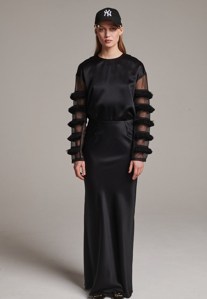 Flowy black skirt with a refined, elongated silhouette. Crafted from lightweight fabric with soft movement and an elegant drape. Front and back darts are intentionally exposed, adding subtle structure and a tailored finish to the fluid shape. A quiet statement piece, effortlessly balancing form and flow.