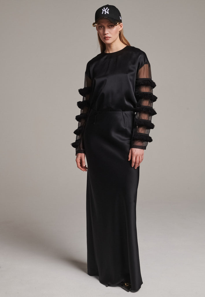 Flowy black skirt with a refined, elongated silhouette. Crafted from lightweight fabric with soft movement and an elegant drape. Front and back darts are intentionally exposed, adding subtle structure and a tailored finish to the fluid shape. A quiet statement piece, effortlessly balancing form and flow.