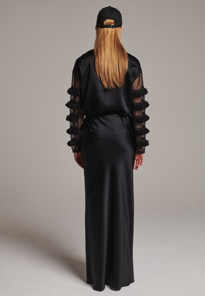 Flowy black skirt with a refined, elongated silhouette. Crafted from lightweight fabric with soft movement and an elegant drape. Front and back darts are intentionally exposed, adding subtle structure and a tailored finish to the fluid shape. A quiet statement piece, effortlessly balancing form and flow.