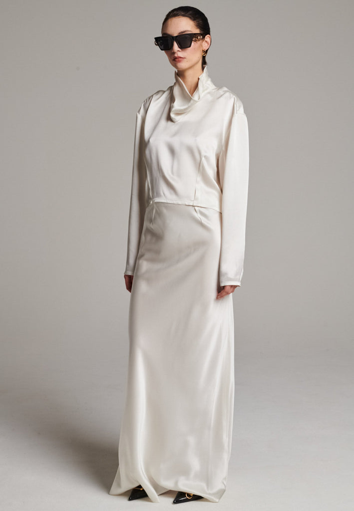 Flowy ivory skirt with a refined, elongated silhouette. Crafted from lightweight fabric with soft movement and an elegant drape. Front and back darts are intentionally exposed, adding subtle structure and a tailored finish to the fluid shape. A quiet statement piece, effortlessly balancing form and flow.