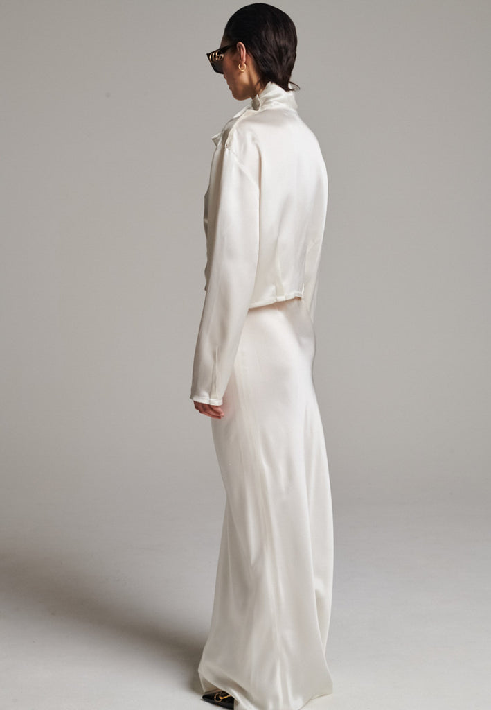 Flowy ivory skirt with a refined, elongated silhouette. Crafted from lightweight fabric with soft movement and an elegant drape. Front and back darts are intentionally exposed, adding subtle structure and a tailored finish to the fluid shape. A quiet statement piece, effortlessly balancing form and flow.