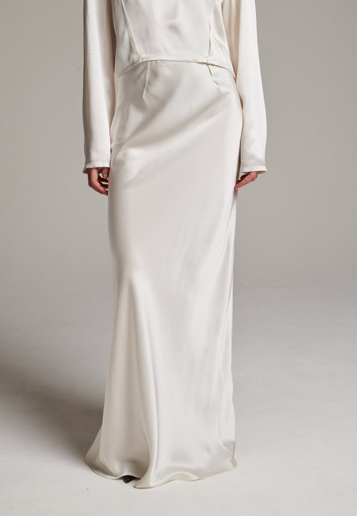 Flowy ivory skirt with a refined, elongated silhouette. Crafted from lightweight fabric with soft movement and an elegant drape. Front and back darts are intentionally exposed, adding subtle structure and a tailored finish to the fluid shape. A quiet statement piece, effortlessly balancing form and flow.