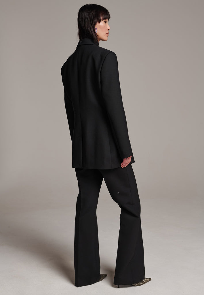 Experience flawless tailoring with this structured blazer, featuring sharp wide shoulders and a subtly cinched waist. Fully satin-lined for added luxury, it includes horn buttons and welt pockets with flaps, along with a back slit for ease of movement. Masterfully crafted in a versatile black hue, this blazer seamlessly complements a range of colors, embodying precision and elegance.