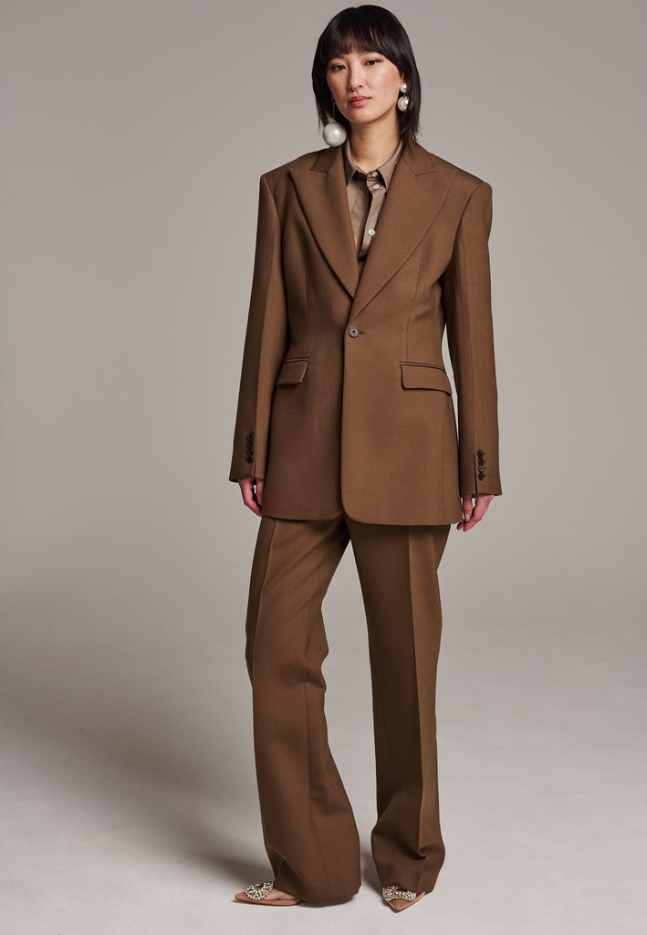 Experience flawless tailoring with this structured blazer, featuring sharp wide shoulders and a subtly cinched waist. Fully satin-lined for added luxury, it includes horn buttons and welt pockets with flaps, along with a back slit for ease of movement. Masterfully crafted in a versatile camel hue, this blazer seamlessly complements a range of colors, embodying precision and elegance.