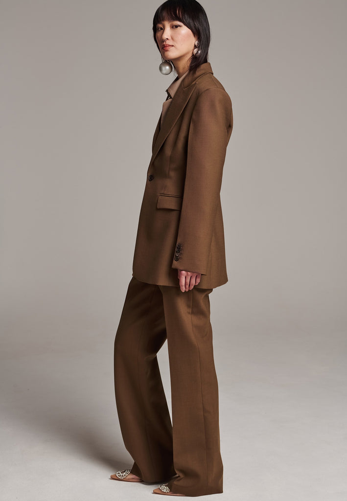 Experience flawless tailoring with this structured blazer, featuring sharp wide shoulders and a subtly cinched waist. Fully satin-lined for added luxury, it includes horn buttons and welt pockets with flaps, along with a back slit for ease of movement. Masterfully crafted in a versatile camel hue, this blazer seamlessly complements a range of colors, embodying precision and elegance.