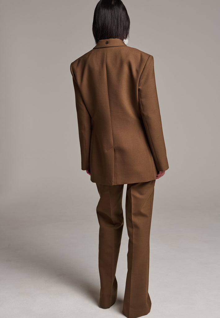 Experience flawless tailoring with this structured blazer, featuring sharp wide shoulders and a subtly cinched waist. Fully satin-lined for added luxury, it includes horn buttons and welt pockets with flaps, along with a back slit for ease of movement. Masterfully crafted in a versatile camel hue, this blazer seamlessly complements a range of colors, embodying precision and elegance.