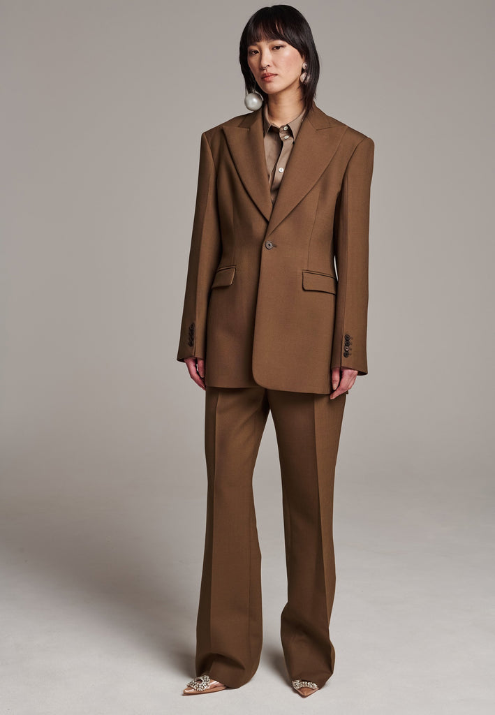 Experience flawless tailoring with this structured blazer, featuring sharp wide shoulders and a subtly cinched waist. Fully satin-lined for added luxury, it includes horn buttons and welt pockets with flaps, along with a back slit for ease of movement. Masterfully crafted in a versatile camel hue, this blazer seamlessly complements a range of colors, embodying precision and elegance.