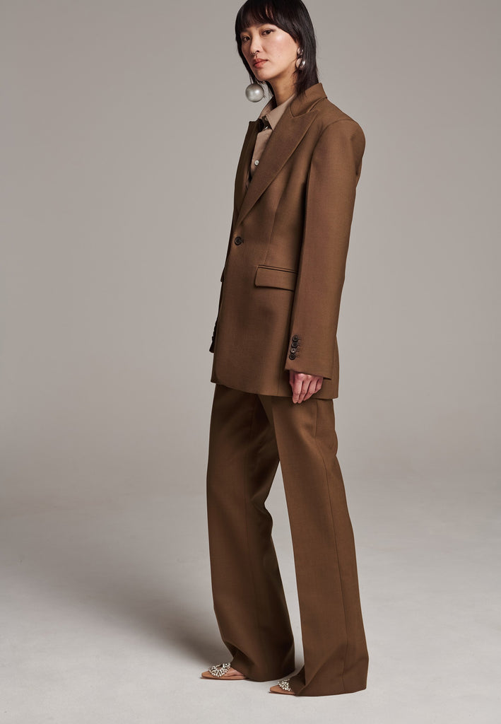Experience flawless tailoring with this structured blazer, featuring sharp wide shoulders and a subtly cinched waist. Fully satin-lined for added luxury, it includes horn buttons and welt pockets with flaps, along with a back slit for ease of movement. Masterfully crafted in a versatile camel hue, this blazer seamlessly complements a range of colors, embodying precision and elegance.