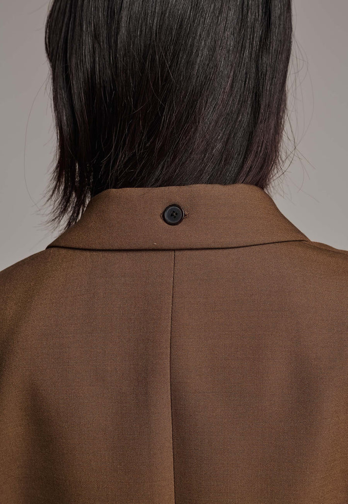 Experience flawless tailoring with this structured blazer, featuring sharp wide shoulders and a subtly cinched waist. Fully satin-lined for added luxury, it includes horn buttons and welt pockets with flaps, along with a back slit for ease of movement. Masterfully crafted in a versatile camel hue, this blazer seamlessly complements a range of colors, embodying precision and elegance.