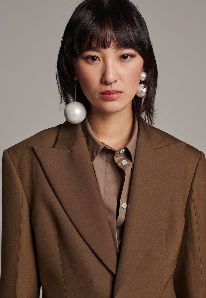Experience flawless tailoring with this structured blazer, featuring sharp wide shoulders and a subtly cinched waist. Fully satin-lined for added luxury, it includes horn buttons and welt pockets with flaps, along with a back slit for ease of movement. Masterfully crafted in a versatile camel hue, this blazer seamlessly complements a range of colors, embodying precision and elegance.