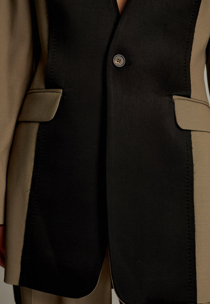 When modern minimalism meets with bold design details. Featuring a unique black panel that cuts vertically down the center front, it creates a striking contrast and edgy focal point. The no-lapel design adds a clean, streamlined aesthetic, while the tailored fit enhances its sophisticated appeal.