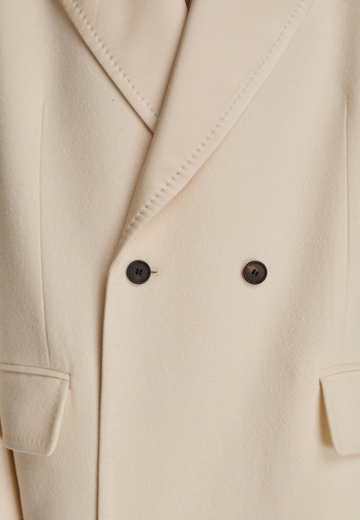 An effortless long coat to slip over any outfit. Detailed by sharp shoulder pads, double-breast fittin and square hole horn buttons. The ankle-grazing length emphasizes the loose fit and the effortless cool over tailoring. FRENKEN makes dressing up every morning easier.