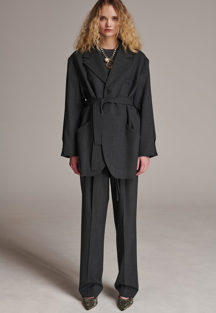 Oversized wrap blazer cut from a wool blend. Designed for an oversized fit, cut to be worn very loose. Padded wide round shoulders that add structure to the loose fit. Knot the inserted belt at the back or front to customize the shape. Horn button closure, welt pocket at front. Central vent at back hem. Full viscose satin lining and detailed with a needlepoint on the belt. This longline silhouette is perfectly tailored and could be your everyday rotation blazer.