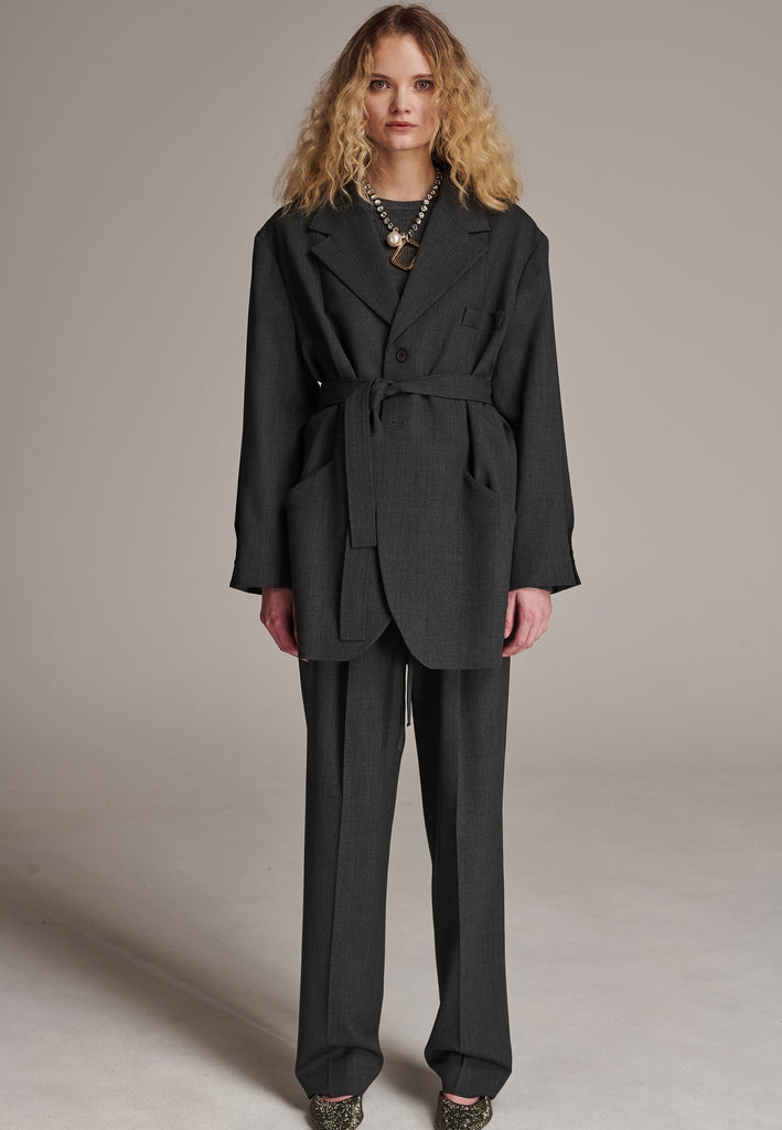Oversized wrap blazer cut from a wool blend. Designed for an oversized fit, cut to be worn very loose. Padded wide round shoulders that add structure to the loose fit. Knot the inserted belt at the back or front to customize the shape. Horn button closure, welt pocket at front. Central vent at back hem. Full viscose satin lining and detailed with a needlepoint on the belt. This longline silhouette is perfectly tailored and could be your everyday rotation blazer.