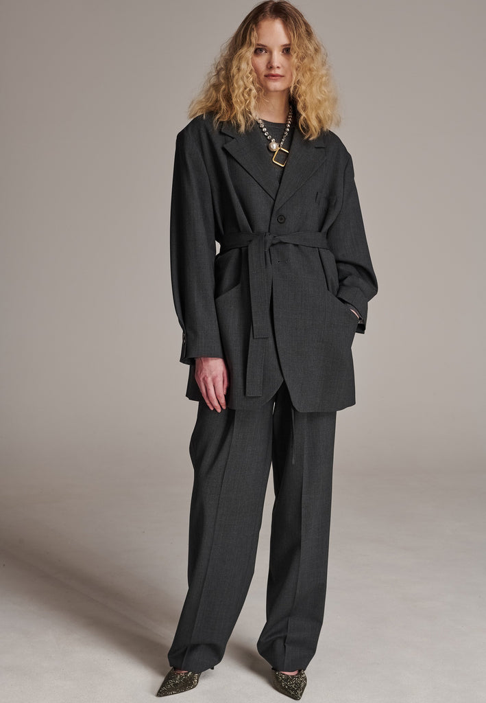Oversized wrap blazer cut from a wool blend. Designed for an oversized fit, cut to be worn very loose. Padded wide round shoulders that add structure to the loose fit. Knot the inserted belt at the back or front to customize the shape. Horn button closure, welt pocket at front. Central vent at back hem. Full viscose satin lining and detailed with a needlepoint on the belt. This longline silhouette is perfectly tailored and could be your everyday rotation blazer.