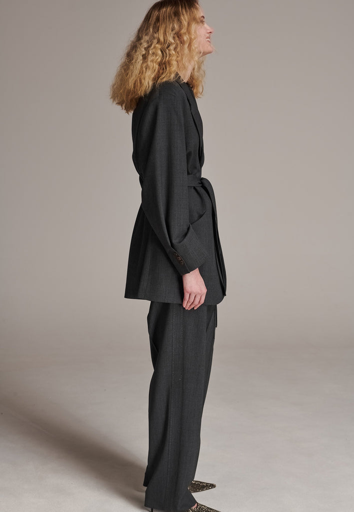 Oversized wrap blazer cut from a wool blend. Designed for an oversized fit, cut to be worn very loose. Padded wide round shoulders that add structure to the loose fit. Knot the inserted belt at the back or front to customize the shape. Horn button closure, welt pocket at front. Central vent at back hem. Full viscose satin lining and detailed with a needlepoint on the belt. This longline silhouette is perfectly tailored and could be your everyday rotation blazer.