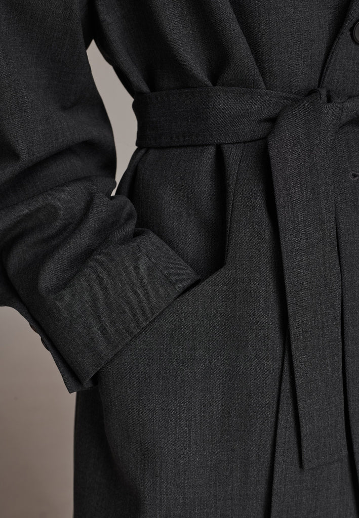 Oversized wrap blazer cut from a wool blend. Designed for an oversized fit, cut to be worn very loose. Padded wide round shoulders that add structure to the loose fit. Knot the inserted belt at the back or front to customize the shape. Horn button closure, welt pocket at front. Central vent at back hem. Full viscose satin lining and detailed with a needlepoint on the belt. This longline silhouette is perfectly tailored and could be your everyday rotation blazer.