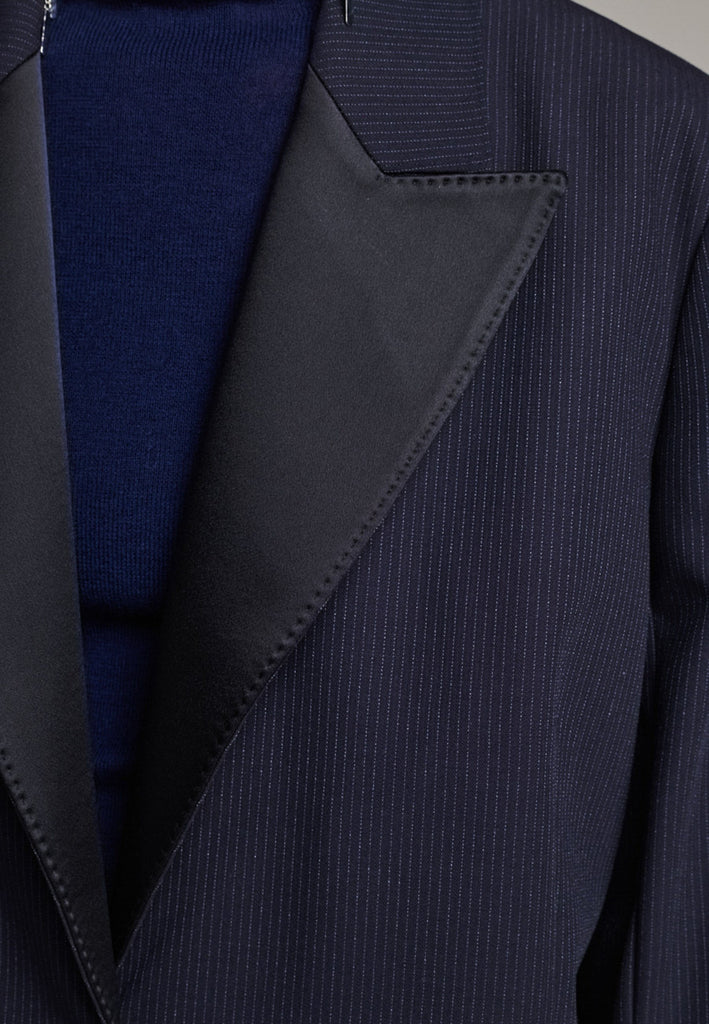 The Devotion Pinstripe Blazer Navy is a bold, reimagined take on classic tailoring. Designed with an oversized silhouette, it features a timeless navy pinstripe base contrasted by sleek black lapels in a subtly glossy fabric, adding a refined, modern twist. The cuffs break convention with a denim finish, introducing a casual edge to the otherwise structured piece. 