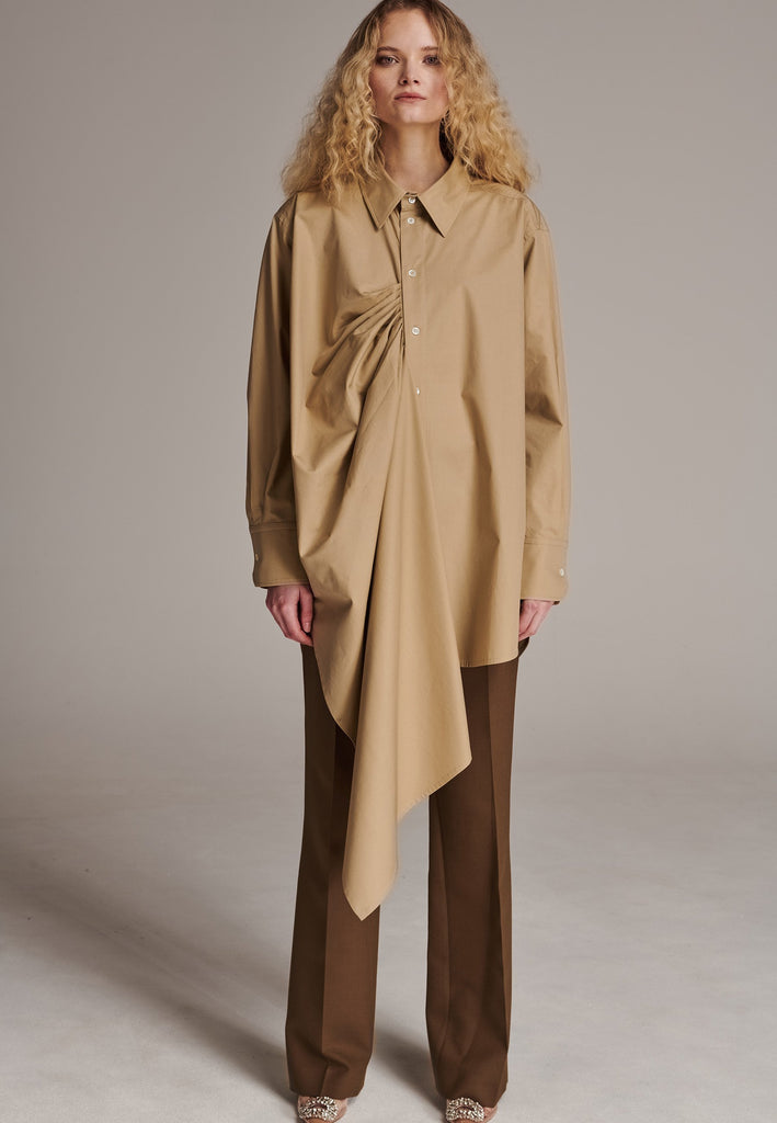 Oversized asymmetric shirt. Specially detailed with a long ruffle effect on one side. It has a button closure to adjust the neckline. 100% Cotton and with an oversized loose shape. Designed for a comfortable and unique fit. A timeless piece.