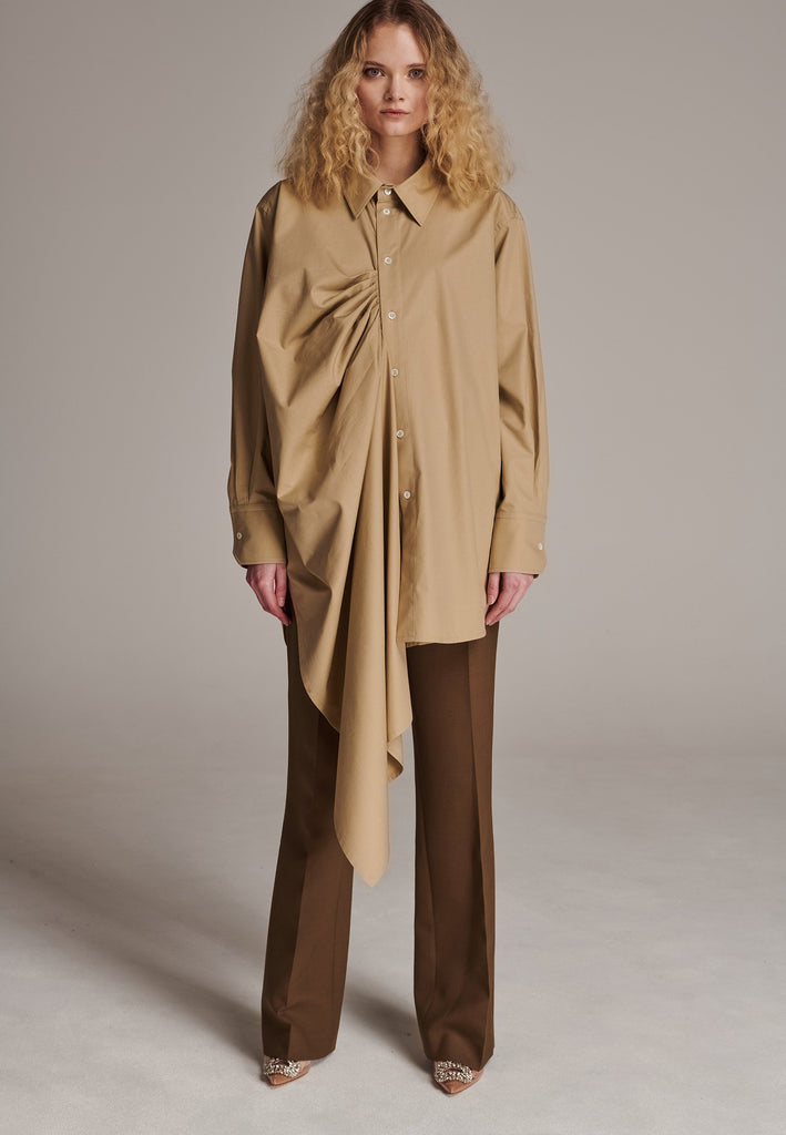 Oversized asymmetric shirt. Specially detailed with a long ruffle effect on one side. It has a button closure to adjust the neckline. 100% Cotton and with an oversized loose shape. Designed for a comfortable and unique fit. A timeless piece.