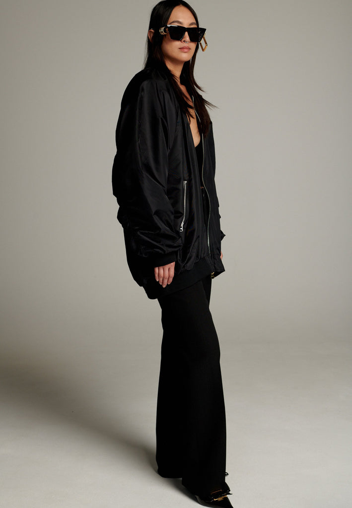A bomber jacket combines modern utility with sleek style, this one features a unique silver and gold zipper detail, adding a touch of metallic contrast to its minimalist design. The bomber silhouette offers a relaxed, casual vibe, while its durable nylon fabric ensures both comfort and functionality. This versatile jacket effortlessly blends style and practicality, making it a timeless addition to any wardrobe.