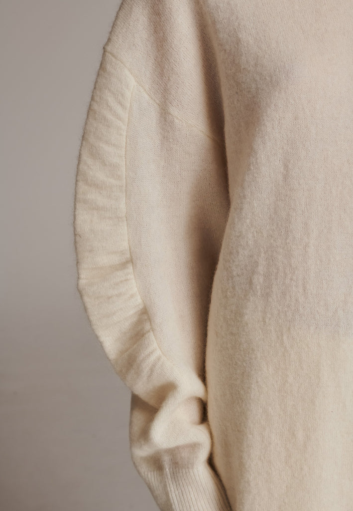 Stay warm and stylish with this oversized knitted sweater, crafted from luxurious virgin merino wool that gives a soft handle. Dropped shoulder seam detailed with gathering at the sleeves, it combines a cozy turtleneck with designer flair. The off-white shade works especially well with off-white tailoring and jeans. Designed for an oversized fit, cut to be worn very loose. Long in sleeves. This piece ensures you’ll stay snug and chic, even on the coldest days.