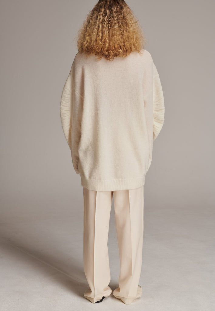 Stay warm and stylish with this oversized knitted sweater, crafted from luxurious virgin merino wool that gives a soft handle. Dropped shoulder seam detailed with gathering at the sleeves, it combines a cozy turtleneck with designer flair. The off-white shade works especially well with off-white tailoring and jeans. Designed for an oversized fit, cut to be worn very loose. Long in sleeves. This piece ensures you’ll stay snug and chic, even on the coldest days.
