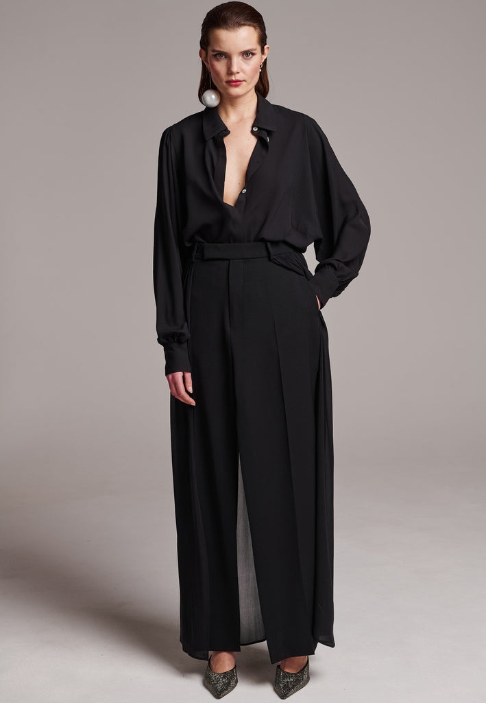 Voluminous poplin shirt with puffed subtle gathered shoulders. Specially detailed with a square armhole seam to create a voluminous sleeve. It has six-hole buttons to adjust the neckline. Cut from 100% silk. Designed for a relaxed fit, cut to be worn very loose. Embellished with a faux pearl on the cuff. This style will go hand in hand with jeans and tailoring.