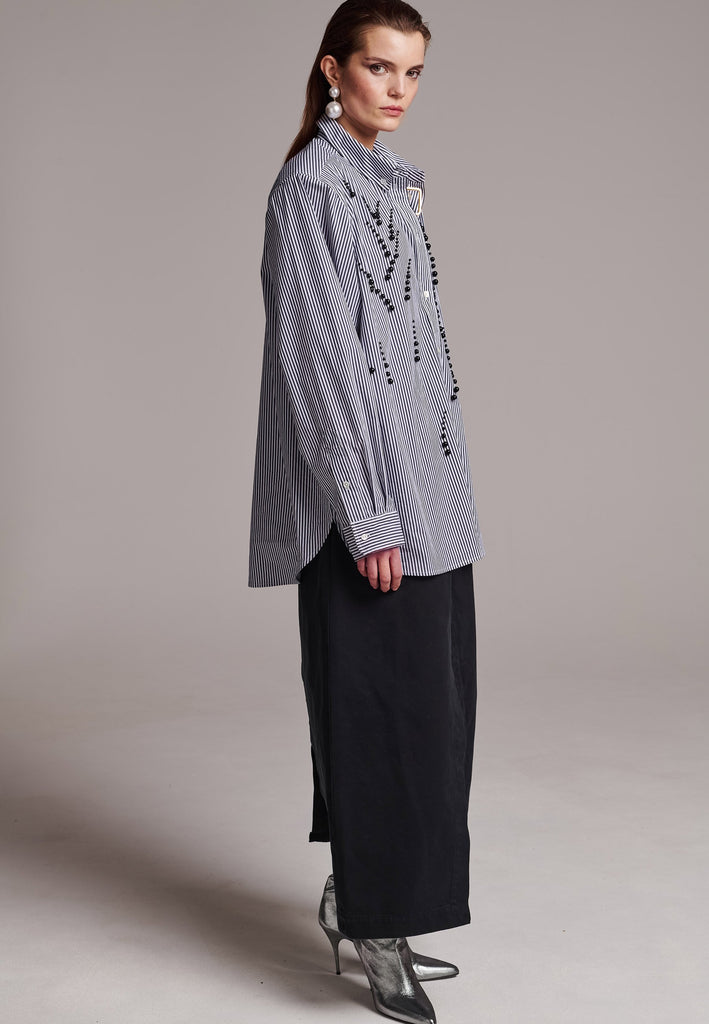 FRENKEN manages to create designs that are somehow classic yet totally modern at the same time. This oversized very easy-to-wear menswear shirt is a true homage to the eighties cut Ralph Lauren men's shirt. Dropped shoulders, with adjustable shoulder pads. Detailed with a mirrored F. Cut from 100% cotton poplin. This Ralf shirt is embellished with faux pearls in an increasing from small to large formation. It's an asset to your wardrobe.