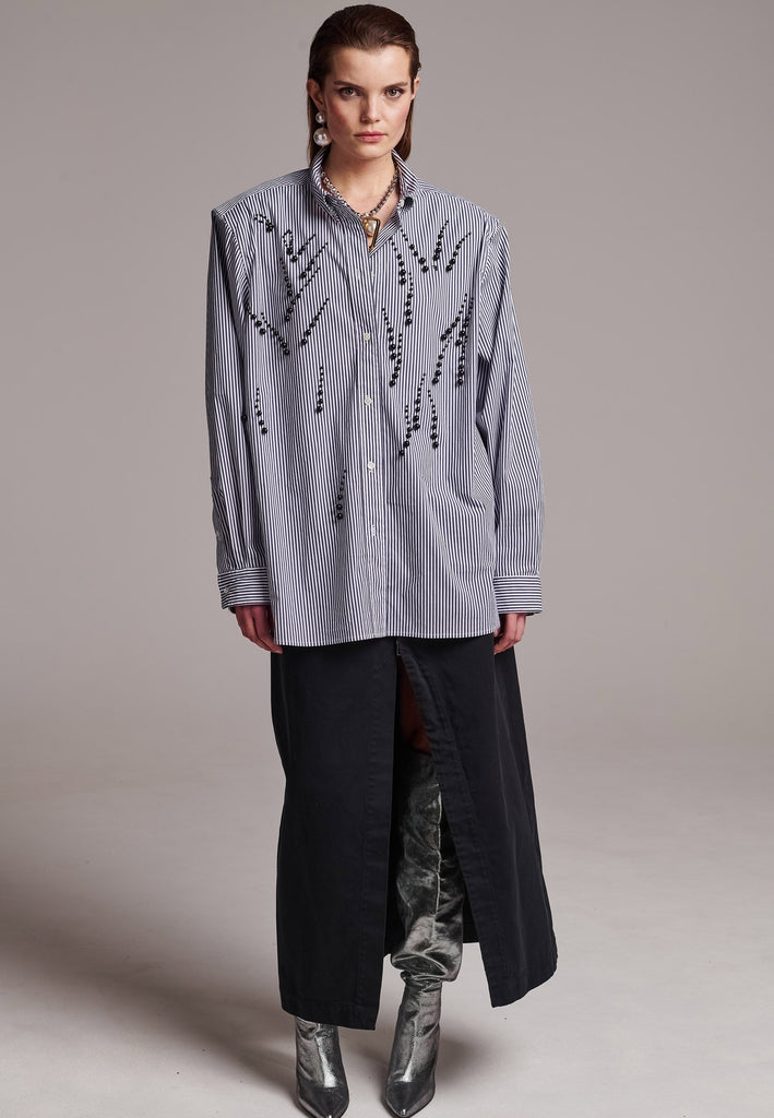 FRENKEN manages to create designs that are somehow classic yet totally modern at the same time. This oversized very easy-to-wear menswear shirt is a true homage to the eighties cut Ralph Lauren men's shirt. Dropped shoulders, with adjustable shoulder pads. Detailed with a mirrored F. Cut from 100% cotton poplin. This Ralf shirt is embellished with faux pearls in an increasing from small to large formation. It's an asset to your wardrobe.