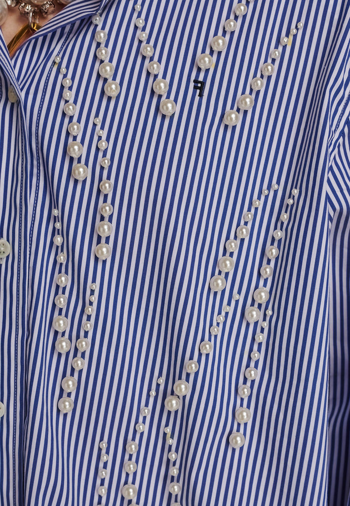 FRENKEN manages to create designs that are somehow classic yet totally modern at the same time. This oversized very easy-to-wear menswear shirt is a true homage to the eighties cut Ralph Lauren men's shirt. Dropped shoulders, with adjustable shoulder pads. Detailed with a mirrored F. Cut from 100% cotton poplin. This Ralf shirt is embellished with faux pearls in an increasing from small to large formation. It's an asset to your wardrobe.