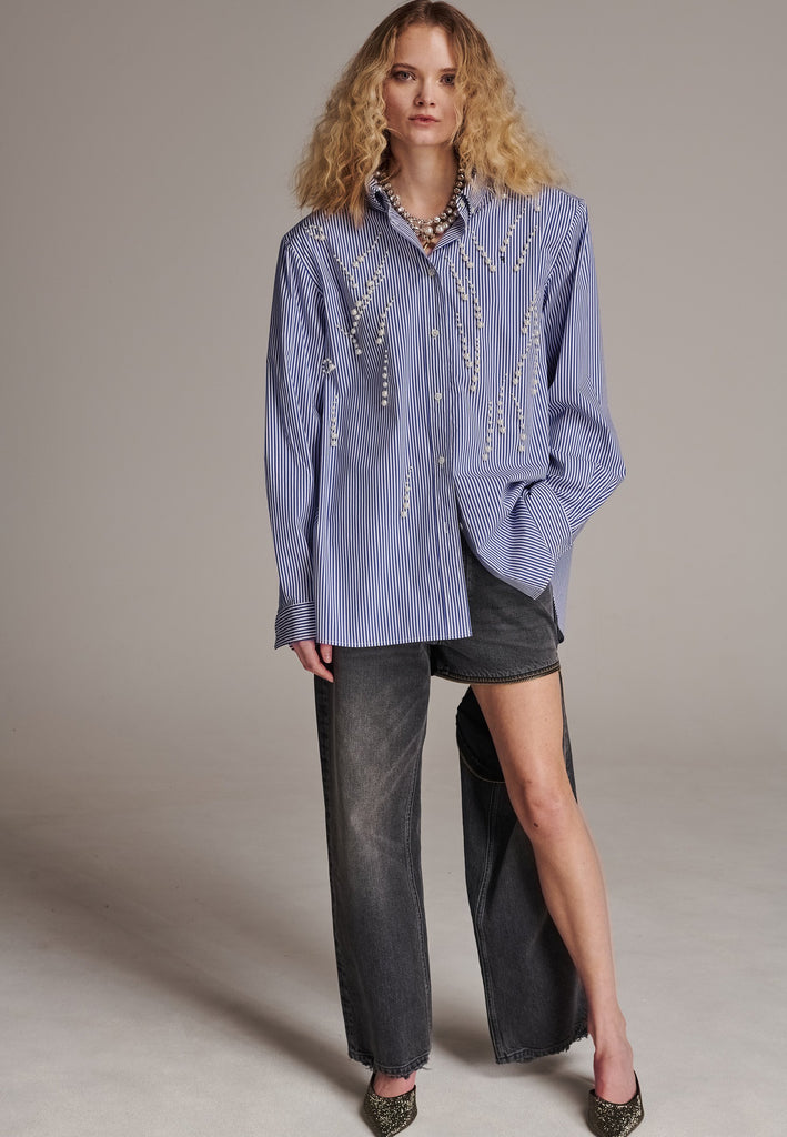 FRENKEN manages to create designs that are somehow classic yet totally modern at the same time. This oversized very easy-to-wear menswear shirt is a true homage to the eighties cut Ralph Lauren men's shirt. Dropped shoulders, with adjustable shoulder pads. Detailed with a mirrored F. Cut from 100% cotton poplin. This Ralf shirt is embellished with faux pearls in an increasing from small to large formation. It's an asset to your wardrobe.