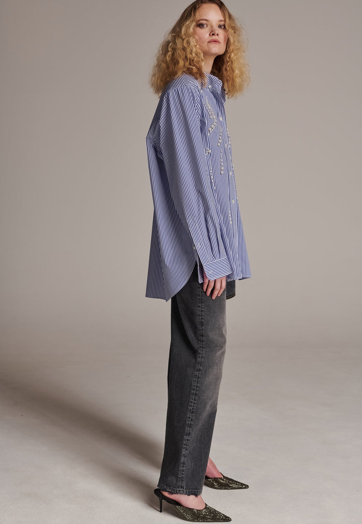 FRENKEN manages to create designs that are somehow classic yet totally modern at the same time. This oversized very easy-to-wear menswear shirt is a true homage to the eighties cut Ralph Lauren men's shirt. Dropped shoulders, with adjustable shoulder pads. Detailed with a mirrored F. Cut from 100% cotton poplin. This Ralf shirt is embellished with faux pearls in an increasing from small to large formation. It's an asset to your wardrobe.