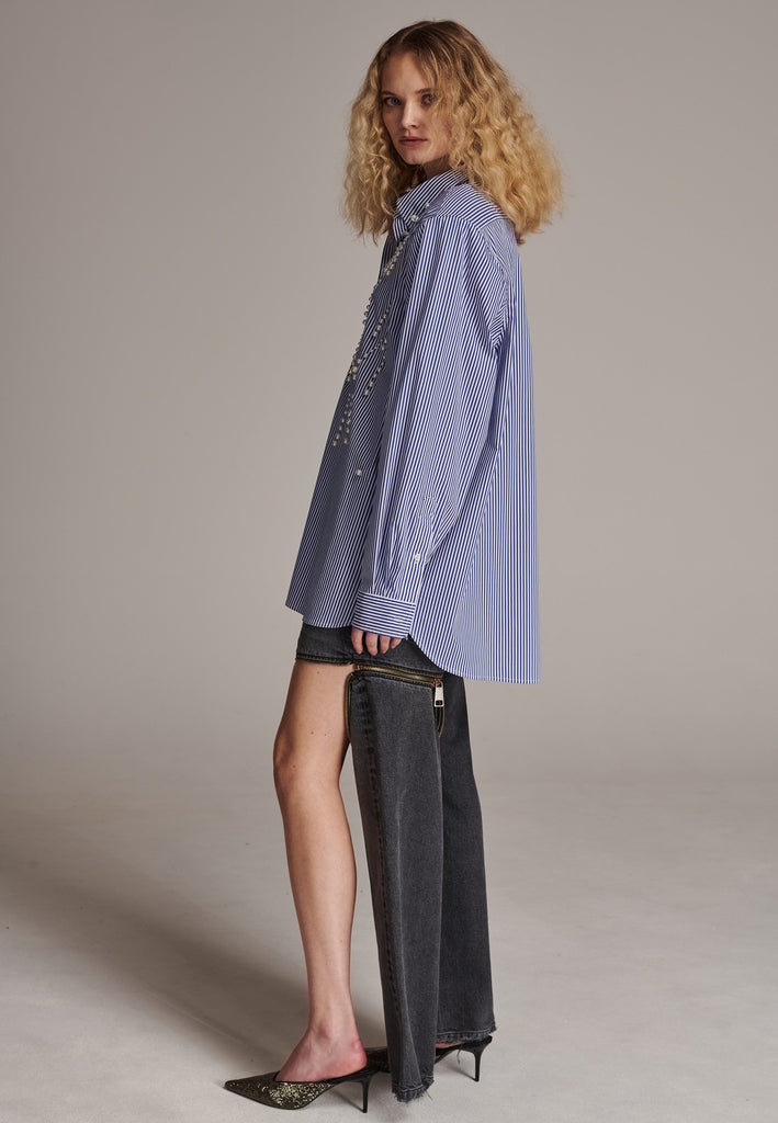 FRENKEN manages to create designs that are somehow classic yet totally modern at the same time. This oversized very easy-to-wear menswear shirt is a true homage to the eighties cut Ralph Lauren men's shirt. Dropped shoulders, with adjustable shoulder pads. Detailed with a mirrored F. Cut from 100% cotton poplin. This Ralf shirt is embellished with faux pearls in an increasing from small to large formation. It's an asset to your wardrobe.