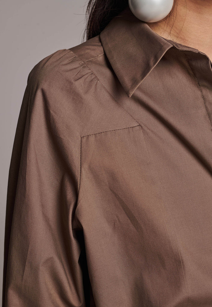 Poplin shirt cut for a relaxed fit with subtle puffed shoulder and some fine gathering. Special detailed with a square armhole seam. It has six-hole buttons to adjust the neckline. Cut from crispy 100% poplin. Embellished with a faux pearl on the left cuff. This style will go hand in hand with garment-dyed skirts and tailoring.