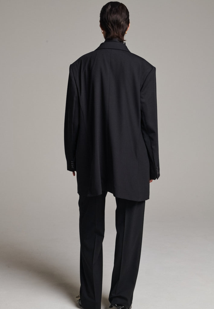 A classic yet oversized blazer, designed to make a bold statement while maintaining timeless appeal. The lower portion of the lapels is crafted from a contrasting shiny fabric, adding an unexpected touch of texture and luxury. The upper part of the collar area is beautifully embellished with gold and silver rings at the tips, offering a refined, modern twist. This piece combines traditional tailoring with avant-garde details, perfect for elevating any outfit with sophistication and edge.