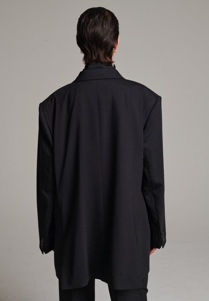 A classic yet oversized blazer, designed to make a bold statement while maintaining timeless appeal. The lower portion of the lapels is crafted from a contrasting shiny fabric, adding an unexpected touch of texture and luxury. The upper part of the collar area is beautifully embellished with gold and silver rings at the tips, offering a refined, modern twist. This piece combines traditional tailoring with avant-garde details, perfect for elevating any outfit with sophistication and edge.