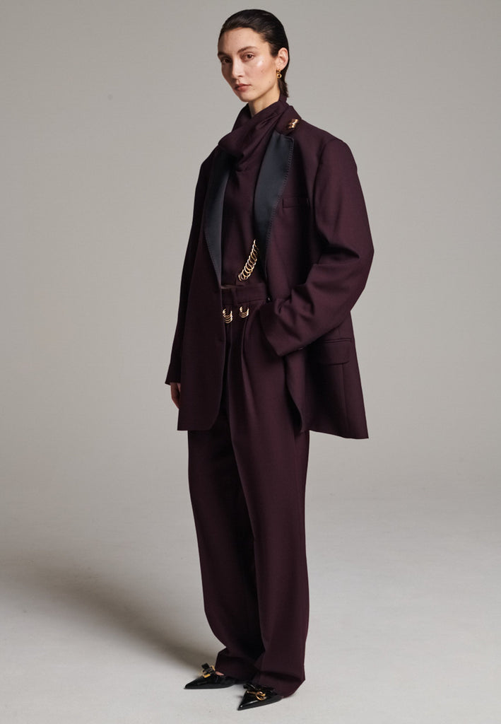 A classic yet oversized blazer, designed to make a bold statement while maintaining timeless appeal. The lower portion of the lapels is crafted from a contrasting shiny fabric, adding an unexpected touch of texture and luxury. The upper part of the collar area is beautifully embellished with gold and silver rings at the tips, offering a refined, modern twist. This piece combines traditional tailoring with avant-garde details, perfect for elevating any outfit with sophistication and edge.
