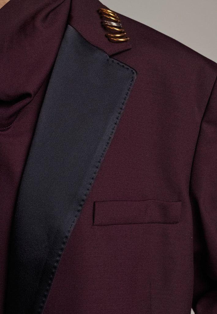 A classic yet oversized blazer, designed to make a bold statement while maintaining timeless appeal. The lower portion of the lapels is crafted from a contrasting shiny fabric, adding an unexpected touch of texture and luxury. The upper part of the collar area is beautifully embellished with gold and silver rings at the tips, offering a refined, modern twist. This piece combines traditional tailoring with avant-garde details, perfect for elevating any outfit with sophistication and edge.