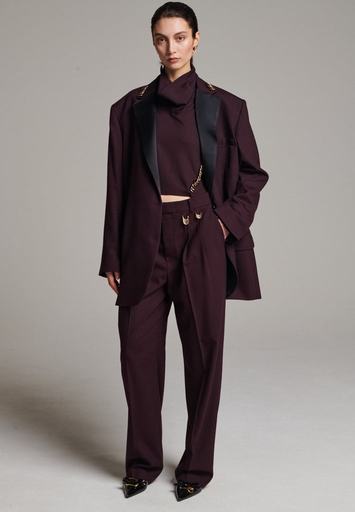 A classic yet oversized blazer, designed to make a bold statement while maintaining timeless appeal. The lower portion of the lapels is crafted from a contrasting shiny fabric, adding an unexpected touch of texture and luxury. The upper part of the collar area is beautifully embellished with gold and silver rings at the tips, offering a refined, modern twist. This piece combines traditional tailoring with avant-garde details, perfect for elevating any outfit with sophistication and edge.