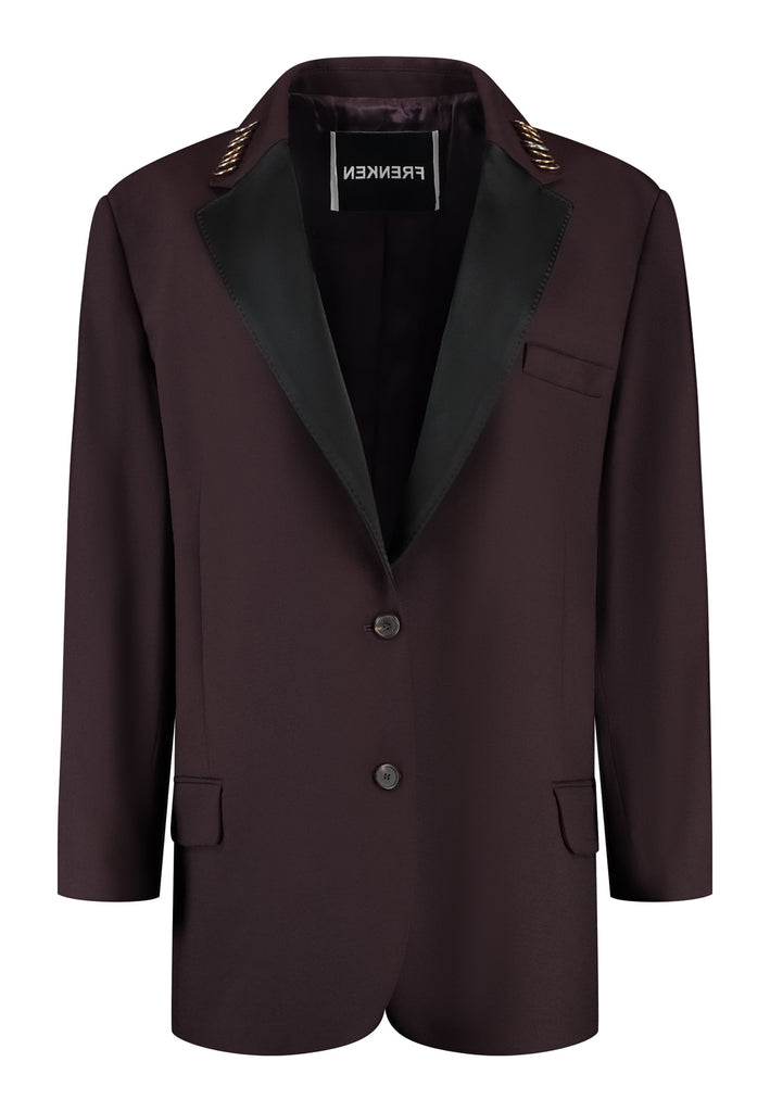 A classic yet oversized blazer, designed to make a bold statement while maintaining timeless appeal. The lower portion of the lapels is crafted from a contrasting shiny fabric, adding an unexpected touch of texture and luxury. The upper part of the collar area is beautifully embellished with gold and silver rings at the tips, offering a refined, modern twist. This piece combines traditional tailoring with avant-garde details, perfect for elevating any outfit with sophistication and edge.